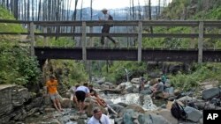 File - Hikers rest in Mineral Creek in Glacier National Park, Montana.