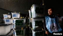 An Afghan election worker stands next to ballot boxes at a counting centre in Kabul, April 6, 2014. 