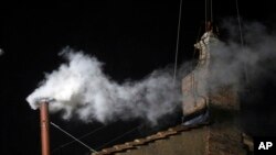 Asap putih terlihat dari cerobong asap di atap Kapel Sistina, di Lapangan Santo Petrus di Vatikan (13/3).