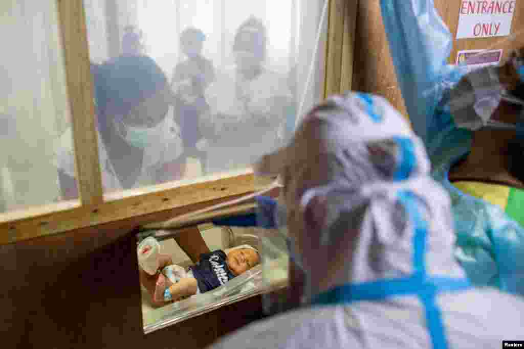 A mother carries her newborn baby towards a makeshift window for health workers to tend to, at the COVID-19 isolation area of the government-run Dr. Jose Fabella Memorial Hospital, amid the coronavirus outbreak, in Manila, Philippines.