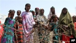 Women and children stand at the edge of an impromptu camp of internally displaced people that has sprung up near the airport, Mogadishu, July 27, 2011
