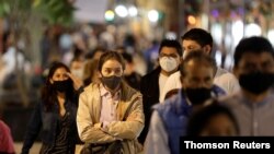 A woman wearing a protective face mask wait to cross a street, as the coronavirus disease outbreak continues, in Mexico City Dec. 11, 2020. 