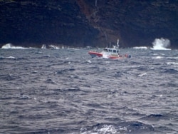 In this photo released by the U.S. Coast Guard, a Coast Guard vessel searches along the Na Pali Coast on the Hawaiian island of Kauai, Dec. 27, 2019, the day after a tour helicopter disappeared with seven people aboard.
