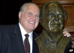FILE - Conservative commentator Rush Limbaugh poses with a bust in his likeness during a ceremony inducting him into the Hall of Famous Missourians in the state Capitol in Jefferson City, May 14, 2012.