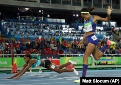 Bahamas' Shaunae Miller falls over the finish line to win gold ahead of United States' Allyson Felix, right, in the women's 400-meter final during the athletics competitions of the 2016 Summer Olympics at the Olympic stadium in Rio de Janeiro, Brazil, Mon