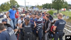 Echanges entre la police allemande et des réfugiés sur le territoire autrichien. Le forces de sécurité allemandes ont arrêtés les migrants sur un pont à la frontière entre l'Autriche et l'Allemagne à Salzbourg, jeudi 17 septembre, 2015. (AP Photo / Kerstin Joensson)