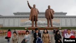 Warga Korea Utara usai memberikan penghormatan kepada patung Kim Il Sung (kiri) dan Kim Jong Il di Pyongyang, Jumat (14/4). Korut siap melakukan percobaan nuklir bawah tanah untuk memperingati HUT Kim Il Sung.