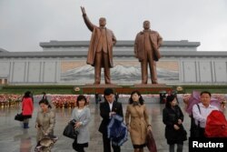 People walk away after paying their respects at the statues of North Korea founder Kim Il Sung, left, and late leader Kim Jong Il in Pyongyang, North Korea, April 14, 2017.
