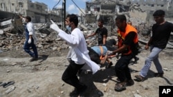Petugas medis Palestina membawa seorang pria yang terluka di Shijaiyah, Gaza City yang terbakar setelah Israel memperluas serangan daratnya melawan Hamas di Jalur Gaza utara, 20 Juli 2014.