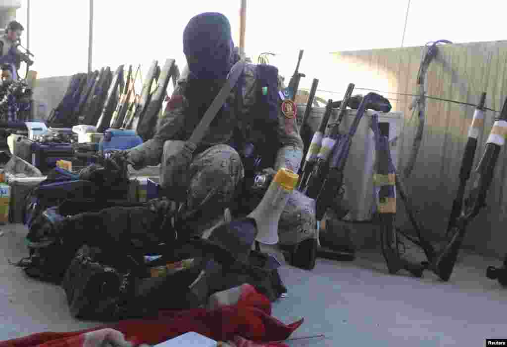 A paramilitary soldier displays weapons recovered during a raid on the Muttahida Qaumi Movement (MQM) political party's headquarters in Karachi March 11, 2015. A Pakistani paramilitary force raided the headquarters of a major political party on Wednesday