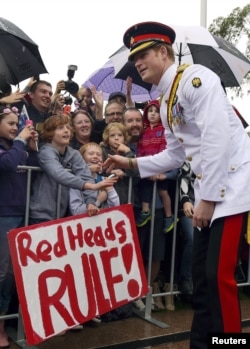 Pangeran Harry dengan publik yang membawa poster bertuliskan 'Rambut Merah Keren' setelah berkunjung ke Taman Makam Pahlawan Perang Australia di Canberra, 6 April 2015.