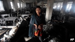 Bangladeshi garment worker Laiju stands inside the damaged Smart Export Garment Ltd. factory where a fire Saturday claimed the lives of seven of her female colleagues in Dhaka, Bangladesh, Sunday, Jan. 27, 2013.
