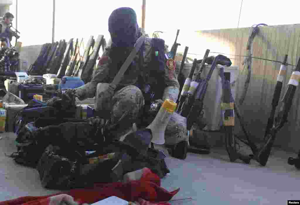 A paramilitary soldier displays weapons recovered during a raid on the Muttahida Qaumi Movement (MQM) political party&#39;s headquarters in Karachi, March 11, 2015.