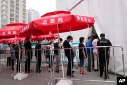 FILE - Residents line up outside a vaccination center in Beijing, June 2, 2021.