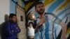 El aficionado argentino Matías Celestino y su hijo Benito Lionel posan para una foto en la habitación de Benito frente a una bandera con la imagen de Lionel Messi en su residencia en Buenos Aires, Argentina, el lunes 3 de junio de 2024. 
