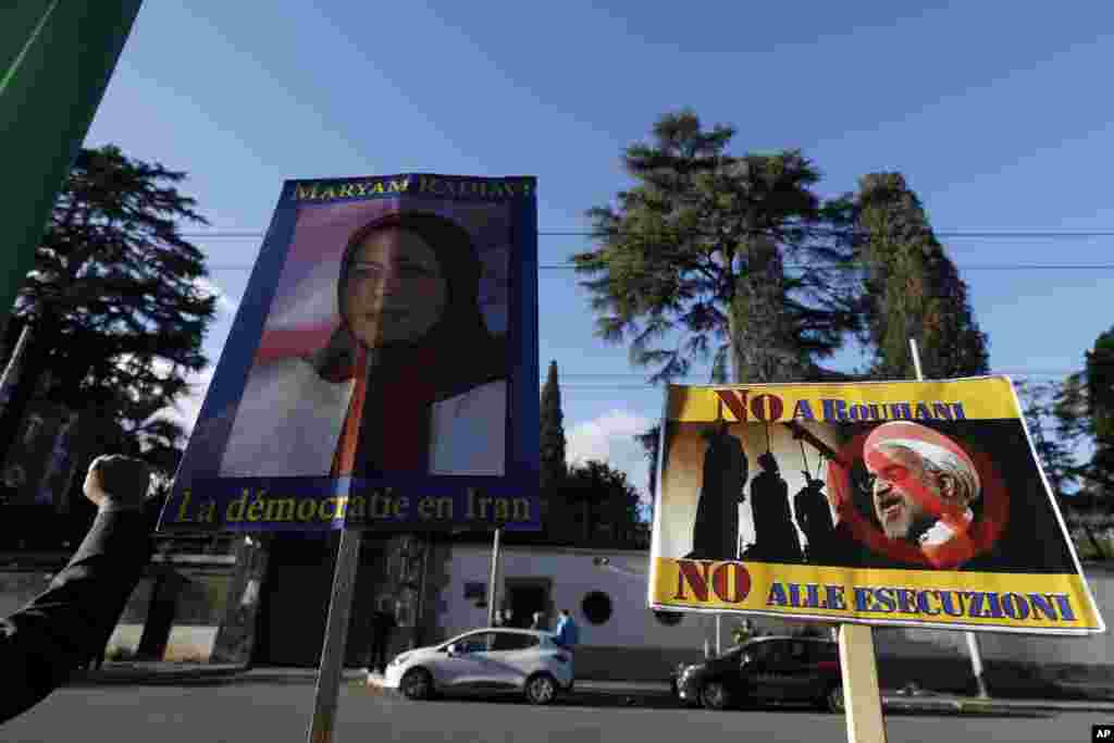 Demonstrators in Rome hold signs showing Maryam Rajavi, head of the Iranian opposition group National Council of Resistance, with writing on placard in French reading, &quot;Democracy in Iran&quot;, left, and another one with a picture of Iran President Hassa