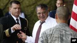 U.S. Secretary of Defense Leon Panetta, center, prepares to give a 'Challenge Coin' to U.S. military personnel stationed at Yokota Air Base in Yokota, Japan, Sept. 17, 2012.