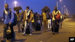 移民携带着随身物品，离开法国北部加莱附近的临时居住营地“丛林”(2016年10月24日)