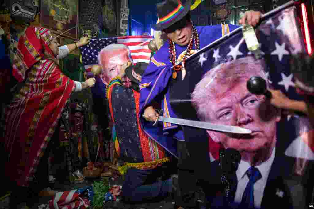 Shamans perform a mystical ritual, holding images of U.S. President Donald Trump and his rival, Democratic presidential candidate Joe Biden, in Lima, Peru, Sept. 16, 2020.