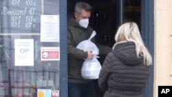 A man wearing a face mask carries a takeaway lunch from a restaurant in Bratislava, Slovakia, Nov. 25, 2021. The Slovak government approved a two-week national lockdown amid a record surge of coronavirus infections.