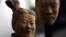 A female terracotta soldier statue holds the mask of a man as it stands in the midst of a terracotta army made up entirely of women and children at a gallery in Beijing's trendy art district, China Saturday Feb. 24, 2007. 