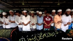 Muslims pray behind the coffins of victims of a fire during a funeral at Yaeway cemetery in Rangoon, April 2, 2013. 