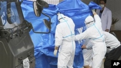 Japan's Self-Defense Force's members and others in protective gear help to transfer workers who stepped into contaminated water on Thursday during their operation at the Fukushima Daiichi nuclear plant, March 25, 2011