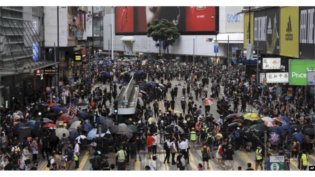 A large group of protesters took over a major street in a Hong Kong shopping district late Sunday afternoon, setting up barricades to block off the area and defend it against police.