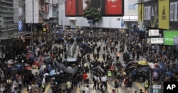 A large group of protesters took over a major street in a Hong Kong shopping district late Sunday afternoon, setting up barricades to block off the area and defend it against police.