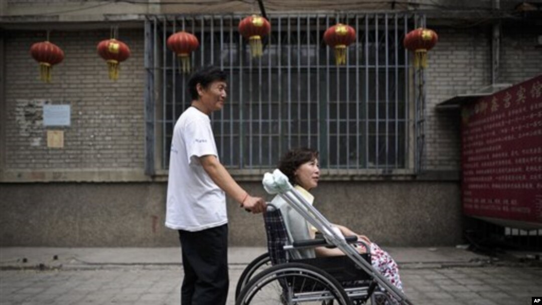 Pada foto yang diambil tanggal 30 Juni 2010 ini, Ni Yulan (duduk di kursi roda) dibantu Don Jiqin, suaminya, menikmati udara sore Beijing (Foto: dok).