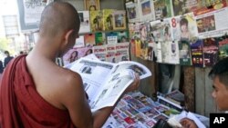 A Buddhist monk reads a journal at a roadside shop in Rangoon, Burma, Tuesday, Feb. 28, 2012. 