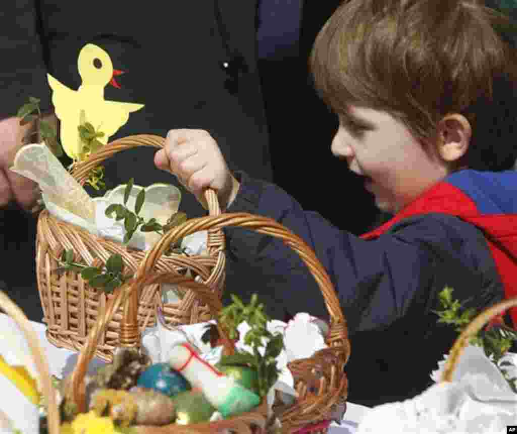 A boy brings a basket with traditional food samples in front of St. Kostka church in Warsaw, Poland, Saturday, April 19, 2014. Traditionally Catholic Poles bring baskets containing mainly an egg, bread, salt, pepper, sausage, horseradish and butter to chu