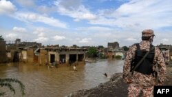 Seorang petugas keamanan berjaga-jaga di daerah pemukiman yang terdampak banjir akibat hujan lebat di kota pelabuhan Karachi Pakistan, 26 Agustus 2020.