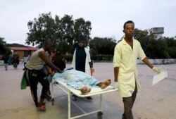 Paramedics and civilians carry an injured person on a stretcher at Madina hospital after a blast at the Elite Hotel in Lido beach in Mogadishu, Somalia, Aug. 16, 2020.