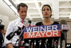 FILE - New York mayoral candidate Anthony Weiner, left, listens as his wife, Huma Abedin, speaks during a news conference at the Gay Men's Health Crisis headquarters, July 23, 2013, in New York. FBI investigators found emails related to Hillary Clinton while investigating a "sexting" case against Weiner.