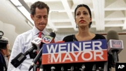 New York mayoral candidate Anthony Weiner, left, listens as his wife, Huma Abedin, speaks during a news conference at the Gay Men's Health Crisis headquarters, July 23, 2013, in New York. 