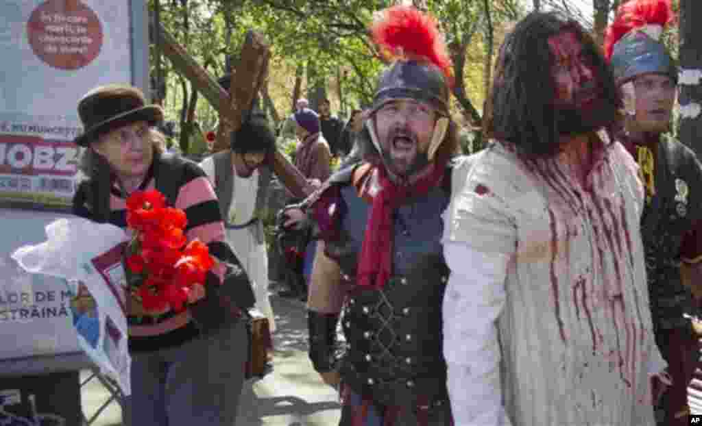A woman reacts as actors pass-by during a reenactment of the crucifixion of Jesus Christ in Bucharest, Romania, Friday, April 13, 2012. Romania's orthodox majority will celebrate Easter on Sunday April 15.(AP Photo/Vadim Ghirda)