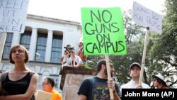 Students holds signs and sex toys as they protest a campus carry law in Austin, Texas, Wednesday Aug. 24, 2016. 