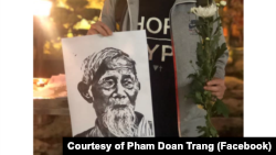 Một thanh niên ở Hà Nội mang hình ông Lê Đình Kình tại buổi lễ tưởng niệm hôm 12 tháng Giêng, 2020. (Photo courtesy of Facebook user Pham Doan Trang)