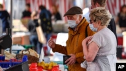 Orang lanjut usia menggunakan masker untuk melindungi dari virus corona tengah berbelanja di pasar di Aachen, Jerman, Kamis, 9 April 2020. (Foto: AP)