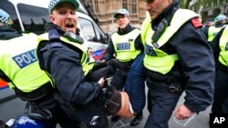 British police officers arrest anti-fascist demonstrators protesting against members of the British National Party [not seen], during a demonstration over the May 22 murder of soldier Lee Rigby by Muslim extremists, in central London, June 1, 2013.