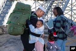 In this photo provided by the U.S. Navy, Hospital Corpsman 1st Class Garion Pequeno reunites with his family after departing the USS Cole, Dec. 23, 2024 at Naval station Norfolk, Va., after a deployment.