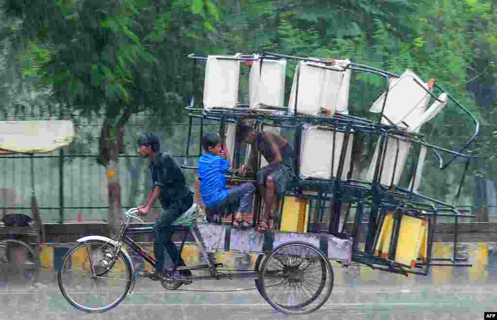 인도 알라하바드에서 한 남성이 인력거에 짐을 가득 실은채 빗속을 운전하고 있다.