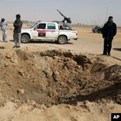Libyan rebels inspect a crater caused by a bomb dropped by a plane in Ajdabiya on Mar 14 2011 as Libyan strongman Moamer Kadhafi's forces shelled rebel positions