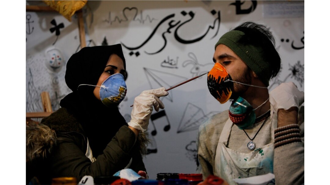 Palestinian artist Samah Said (L) paints an N95 protective mask worn by fellow artist Dorgham Krakeh (R) for a project raising awareness about the COVID-19 coronavirus pandemic, in Gaza City on March 24, 2020.