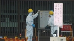 FILE - Security guards are seen at one of exterior doors leading to the Fukushima Daiichi nuclear power plant. (Steve Herman/VOA)