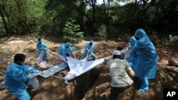 Volunteers and workers bury the body of a COVID-19 victim in Chennai, India, June 5, 2021. 