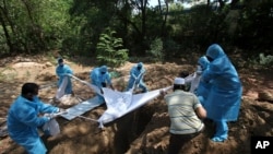 Volunteers and workers bury the body of a COVID-19 victim in Chennai, India, Saturday, June 5, 2021. (AP Photo/R. Parthibhan)