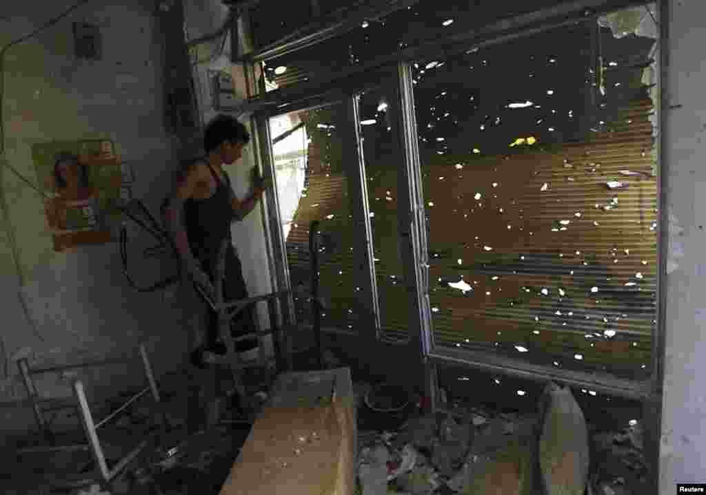 A Free Syrian Army fighter carries his weapon as he peeks out from a damaged shop in Deir al-Zor, Oct. 6, 2013. 