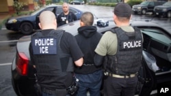 FILE - In this photo released by U.S. Immigration and Customs Enforcement, foreign nationals are arrested during a raid aimed at immigration fugitives, re-entrants and at-large criminal aliens in Los Angeles, Feb. 7, 2017. 